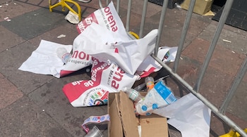 Propaganda impresa con el nombre de Morena, botellas de plástico y cajas de cartón tiradas en el suelo junto a una valla metálica.