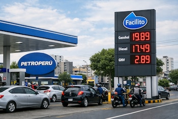 Vista frontal de una estación de servicio Petroperú en Lima con autos y motos en fila. Un cartel digital muestra precios altos de gasohol, diésel y GNV, con el logo Facilito. Cielo nublado.