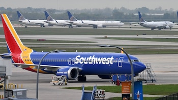 Un avión Boeing 737 de Southwest Airlines azul, amarillo y rojo en pista de aeropuerto. Detrás, se observan tres aviones Boeing 737 blancos de United Airlines