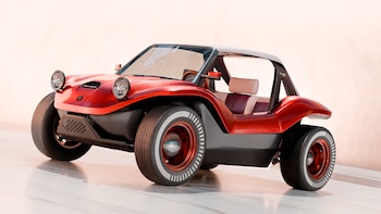Un buggy moderno, color rojo metálico y negro, con neumáticos de banda blanca, llantas rojas y asientos claros, visto desde el frente en un estudio