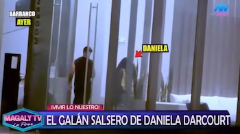 Dos personas caminando dentro de un edificio moderno con grandes ventanales. La mujer está señalada con el nombre "Daniela". Textos superpuestos de Magaly TV
