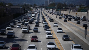 Vista aérea de una autopista de varios carriles con denso tráfico de coches, SUVs y camiones. La carretera está llena de vehículos en ambas direcciones