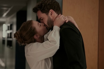 Primer plano de un hombre con barba y una mujer besándose tiernamente con los ojos cerrados; ella le rodea el cuello con los brazos