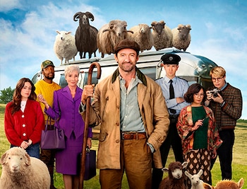 Hugh Jackman, Emma Thompson, Nicholas Galitzine y cinco personas más posan con ovejas frente a un tráiler en un campo