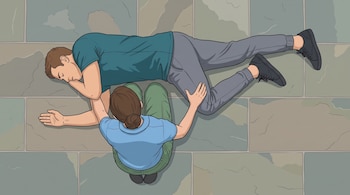 Ilustración desde una vista cenital de una mujer arrodillada que asiste a un hombre acostado de costado sobre un piso de piedra.