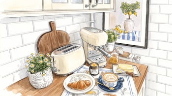 Ilustración de una encimera de cocina con tostadora, cafetera, taza de café, croissant, flores, mantequilla, miel y un cuadro de limonero.