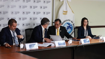 Cuatro personas sentadas en mesa de reunión, con tres hombres y una mujer. Un fondo con el logo del Ministerio de Salud Pública de Guatemala es visible