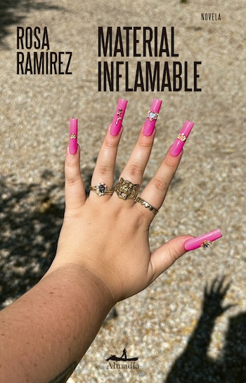 Una mano con uñas largas de color rosa intenso y adornos dorados se extiende sobre un suelo de piedra junto al texto Material inflamable