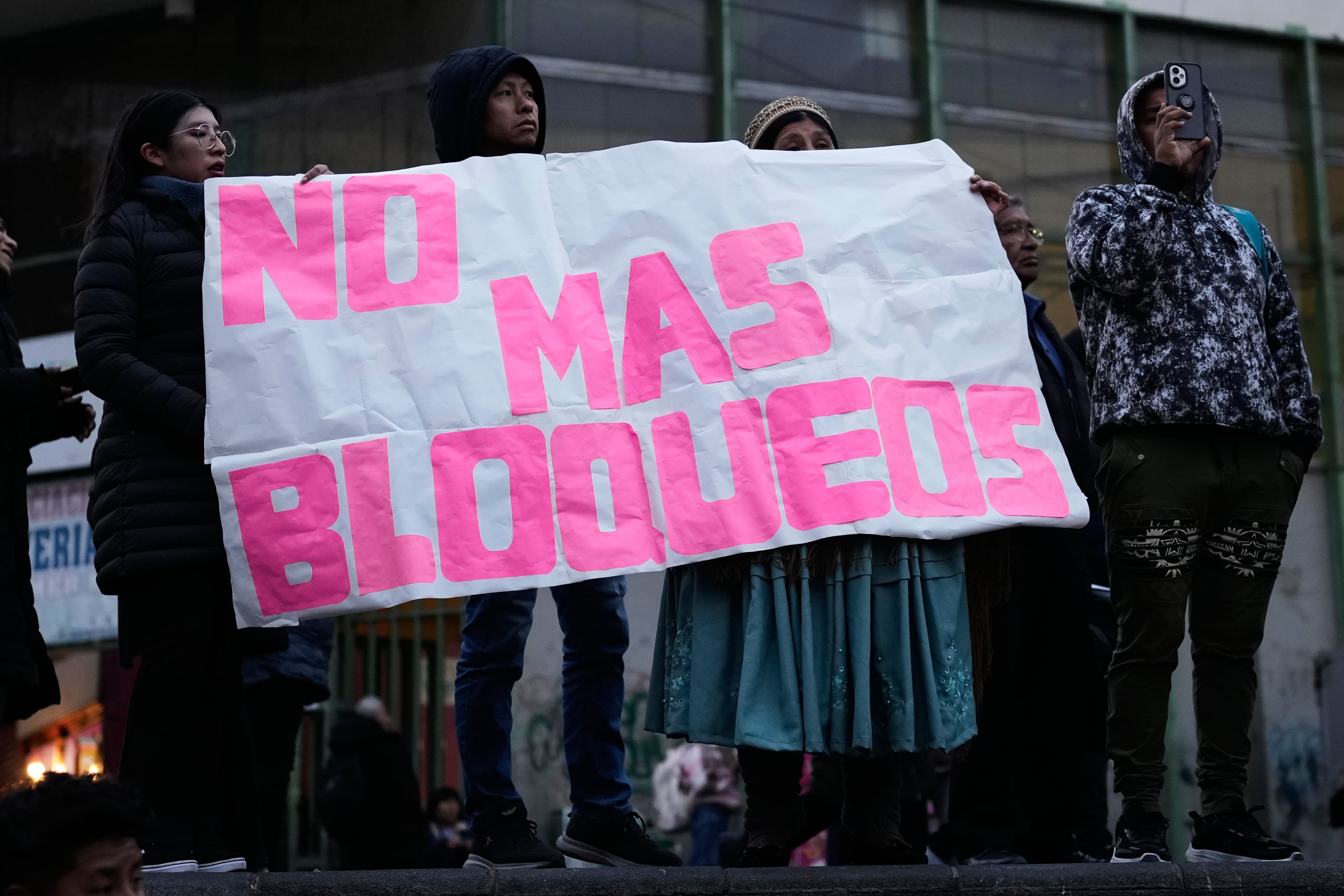 Manifestantes sostienen un cartel que dice en español: