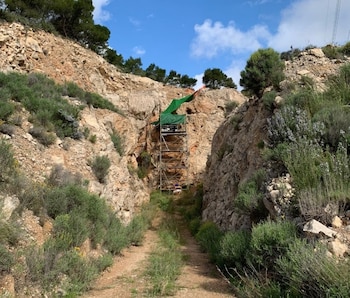 Un paisaje de rocas. Al fondo se observa un andamio de metal donde se localiza la entrada al yacimiento de Quibas