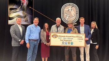 Siete personas posan con un cheque de $10.000 y trofeo. Detrás, logo de Comisión de Florida. Recuadro con persona sujetando una serpiente