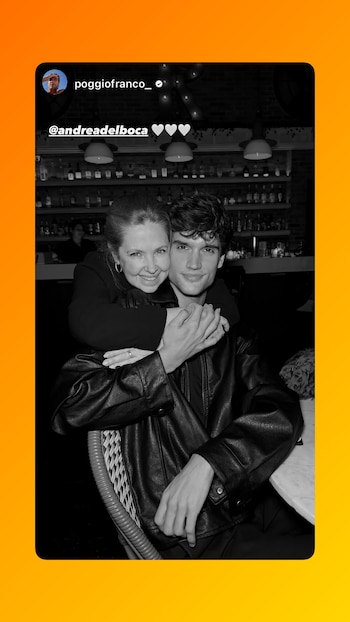 Imagen en blanco y negro de Andrea del Boca con el cabello recogido abrazando a Franco Poggio, ambos sonrientes en un bar con botellas de fondo