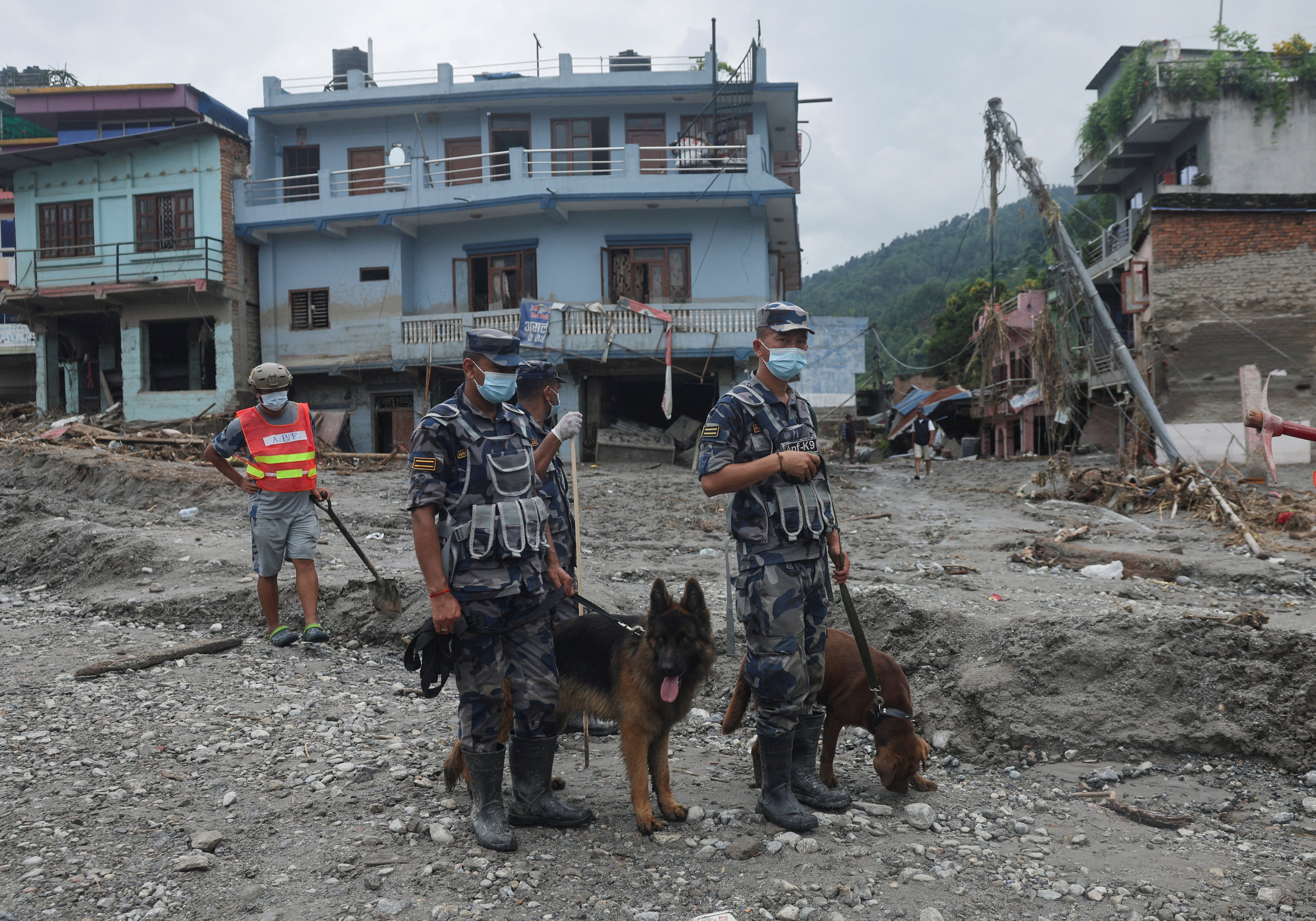 Agentes de la Fuerza de Policía Armada permanecen junto a perros rastreadores en el lugar afectado por inundaciones repentinas y deslizamientos de tierra en Devighat, distrito de Nuwakot, Nepal, el 29 de agosto de 2026 (REUTERS/Francis Mascarenhas)