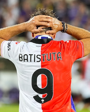 Espalda de una persona con las manos en la cabeza, vestida con una camiseta blanca y roja con el apellido Batistuta y el número nueve