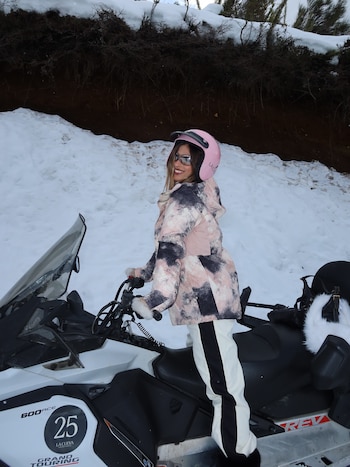 Poggio manejó una moto de nieve con casco rosa y campera en tonos rosados y grises durante el recorrido por los cerros