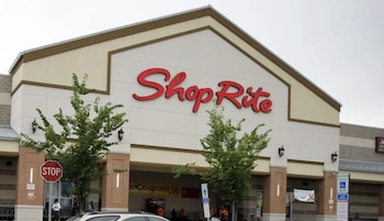 Fachada de un edificio comercial con el letrero de ShopRite en letras rojas, árboles pequeños y señales de tránsito