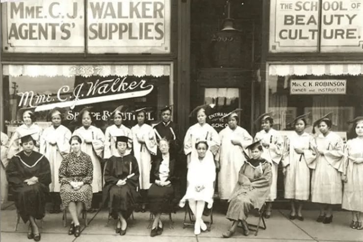 Un grupo de estudiantes y profesoras posa frente a la escuela de belleza y tienda de suministros de Madam C.J. Walker, símbolo del emprendimiento femenino afroamericano