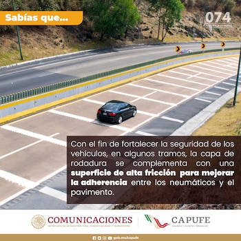 Vista aérea de un automóvil negro transitando por una autopista de múltiples carriles con barreras verdes y amarillas, y marcas blancas en la calzada