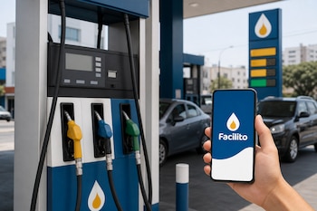 Mano que sostiene un teléfono celular con la pantalla de Facilito junto a un surtidor de gasolina con mangueras de colores.