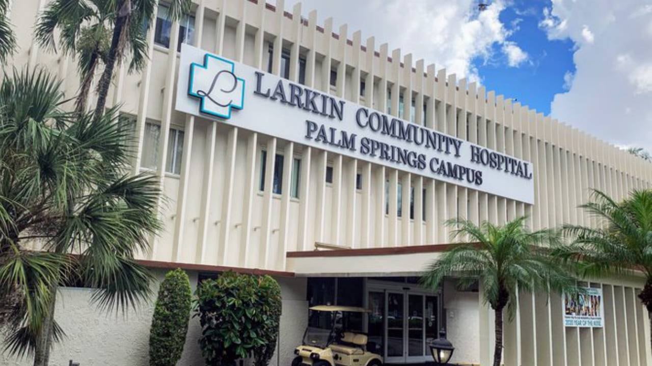 El exterior del Larkin Community Hospital Palm Springs Campus en Hialeah, destacando su entrada principal y el cartel distintivo de la institución bajo un cielo parcialmente nublado. (Larkin Community Hospital )
