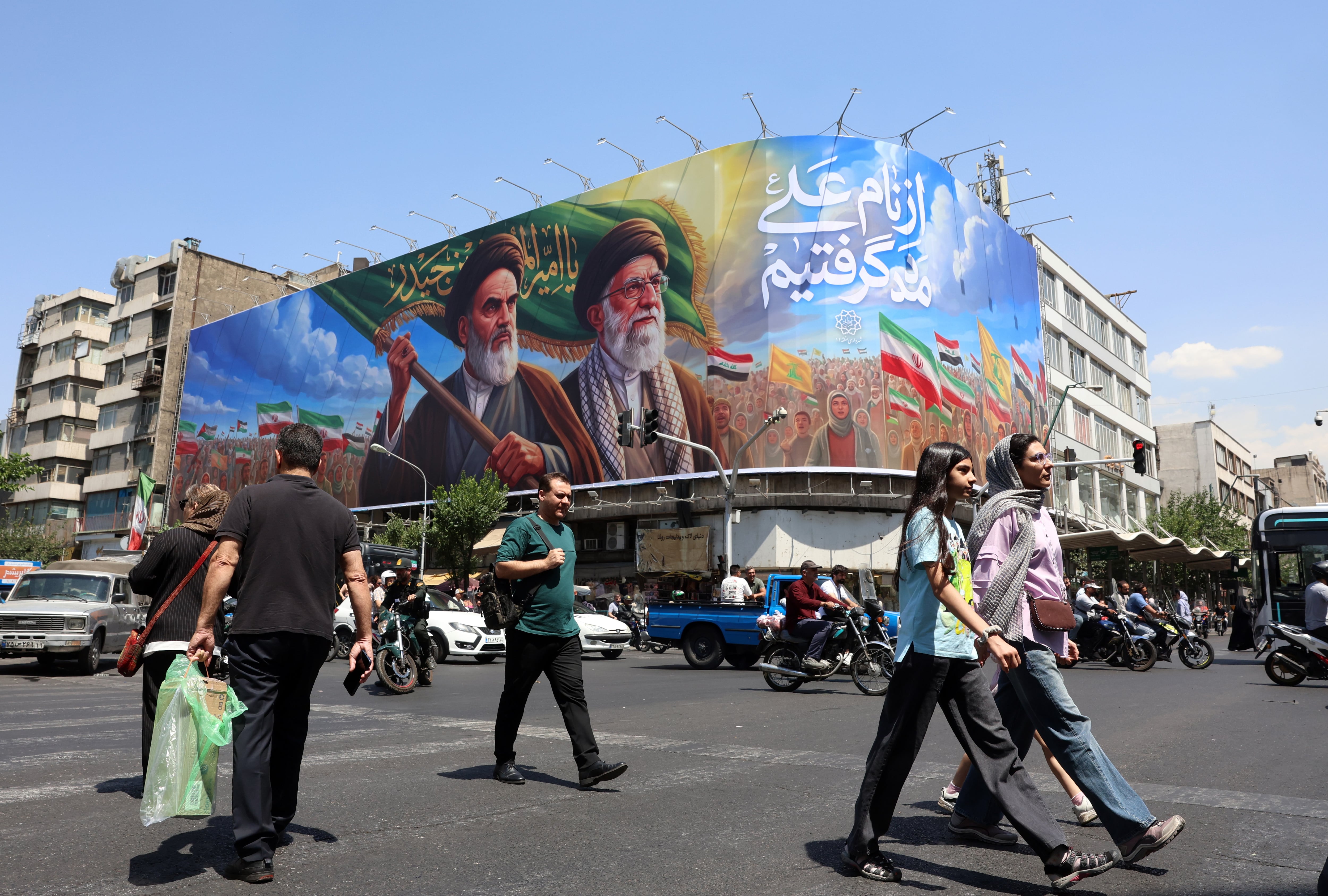 Ciudadanos iraníes pasan junto a una gran valla publicitaria en Teherán (EFE/EPA/ABEDIN TAHERKENAREH)