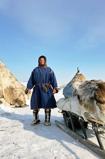 Grupo de personas, algunas vestidas con trajes tradicionales Nenet, posan sonrientes en la nieve frente a una tienda cónica, sosteniendo una camiseta de fútbol de Messi