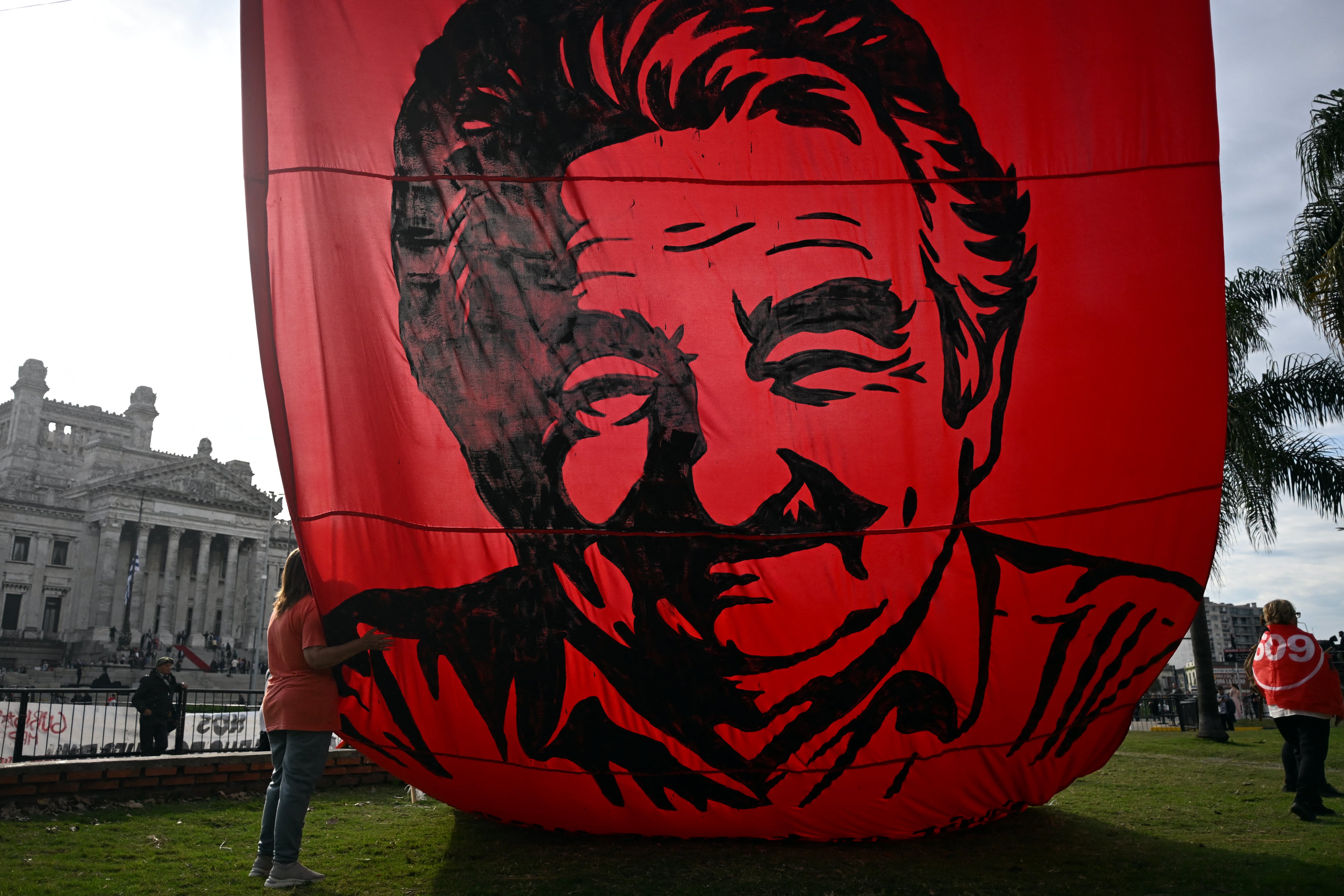 Una mujer abraza una enorme pancarta con la imagen del expresidente uruguayo José