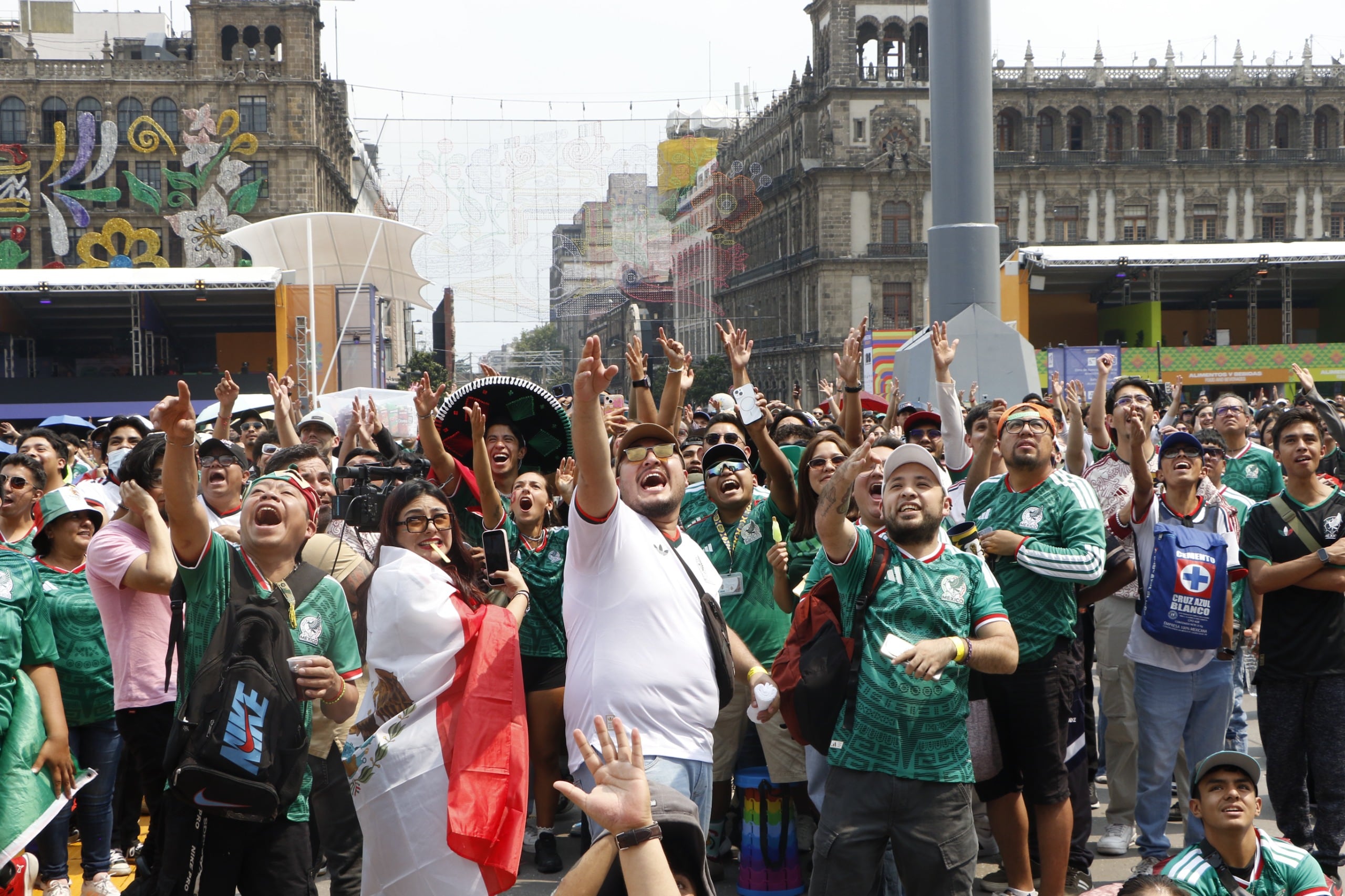 Una multitud de aficionados mexicanos con camisetas verdes de la selección nacional celebra con las manos en alto durante el fan fest organizado en el Zócalo de la Ciudad de México por el partido contra Corea del Sur. (Jefatura Gobierno CDMX)