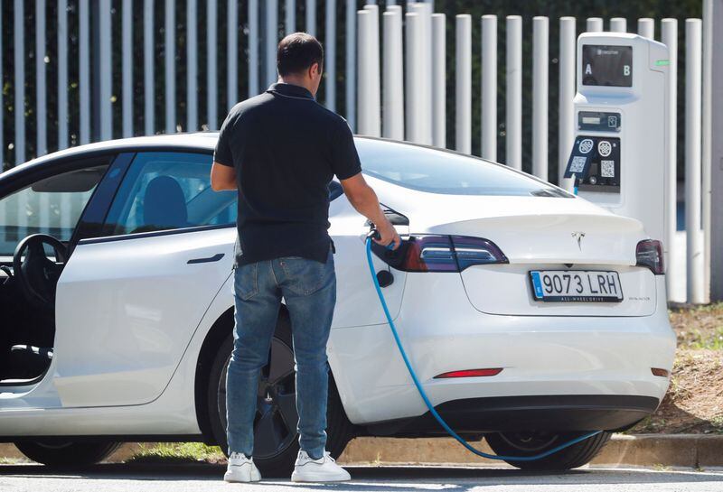 Un hombre retira un cable después de cargar un coche eléctrico en un punto de carga público en Barcelona. (Albert Gea/Reuters)