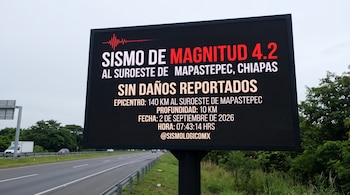 Un cartel electrónico en la orilla de una carretera muestra un texto con la información de un sismo junto a un gráfico de onda sísmica.
