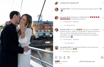 Una pareja se abraza en un puente mientras la mujer muestra un anillo de compromiso en su mano, junto a comentarios de una publicación de Instagram