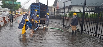 Cuadrillas de Desechos Sólidos ejecutan labores de desagüe en una calle inundada de San Salvador, tras las intensas lluvias registradas en la capital (Cortesía @alcaldia_ss).