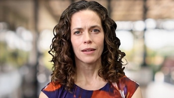 Close de Layla Mashkoor, mulher de cabelo castanho e camisa estampada, olhando para a câmera fora de foco no fundo