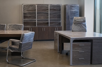 Muebles de oficina de madera, que incluyen escritorios, sillas y estantes, envueltos en plástico transparente.