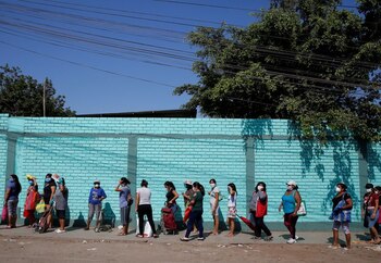Mujeres utilizando mascarillas hacen fila