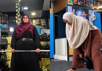 Dos mujeres con hiyab en un gimnasio: una sostiene una barra con discos de frente y la otra se inclina para levantar una pesa rusa