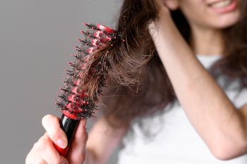 Una mujer pierde mucho pelo mientras se peina (Magnific)
