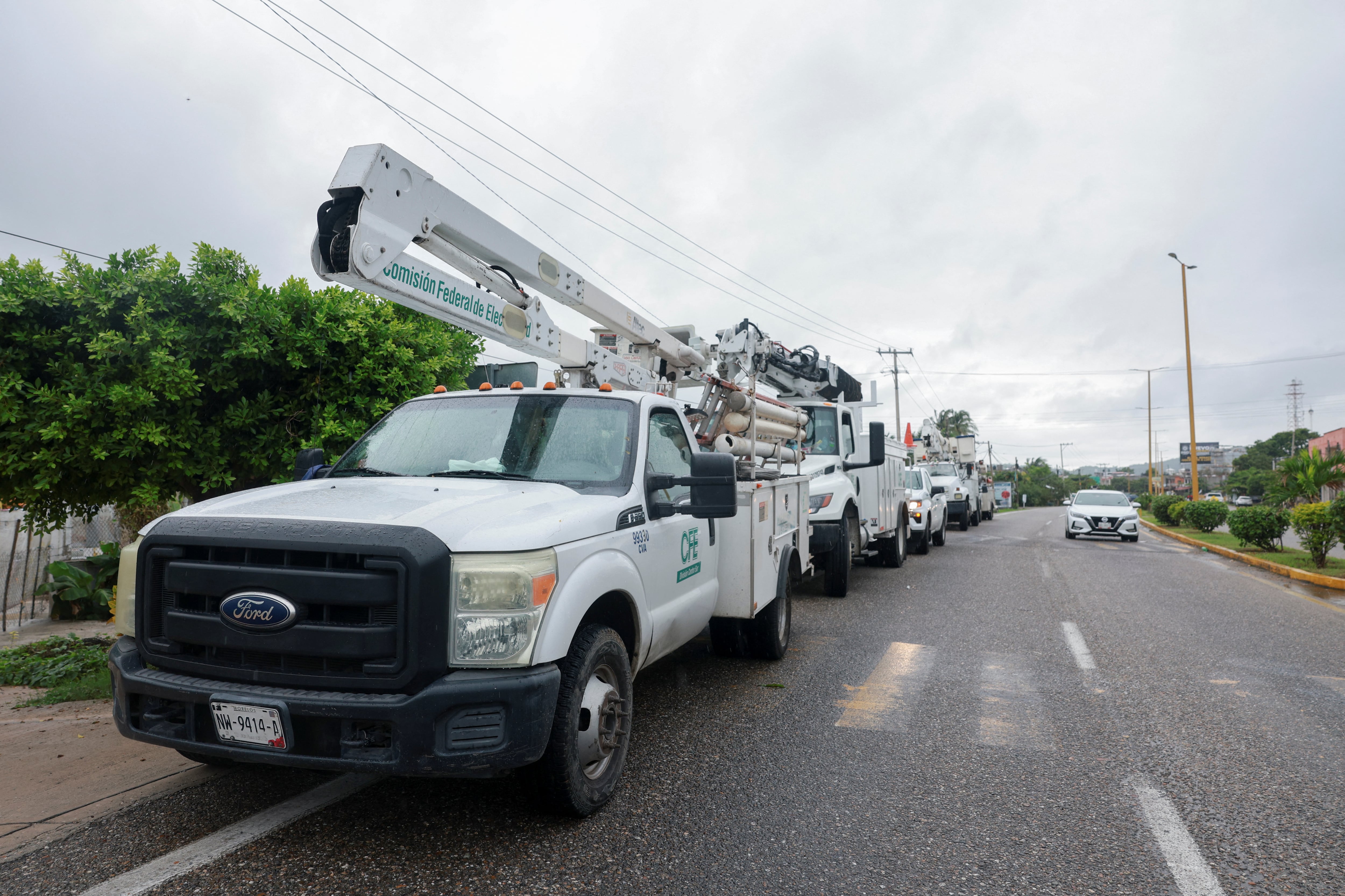 Los camiones de la Comisión Federal de Electricidad (CFE) de México están estacionados junto a la carretera en la ciudad de San Marcos, estado de Guerrero, el día en que el huracán Erick tocó tierra en la costa del estado de Oaxaca, México, el 19 de junio de 2025.REUTERS/Henry Romero