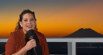 La presidenta del Instituto Salvadoreño de Turismo presenta la oferta turística para las vacaciones agostinas, con el volcán Chinchontepec iluminado por el amanecer (Cortesía: Entrevista AM).