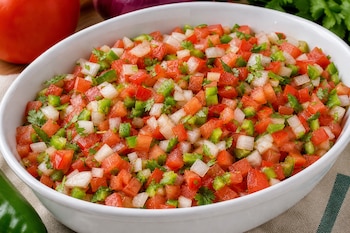 Fuente blanca con picadillo de tomate, cebolla, pimiento verde y cilantro.