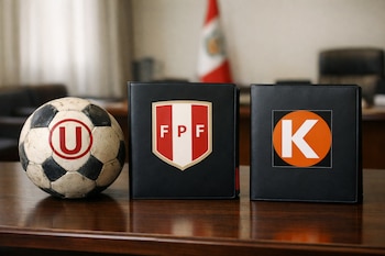 Sobre una mesa de madera oscura, una pelota de fútbol gastada con logo de Universitario, una carpeta con el escudo de la FPF y otra con el logo K de Fuerza Popular.