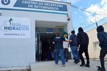Fachada de edificio blanco con cartel "CENTRO DE RECEPCIÓN DE RETORNADOS" y logo de "INSTITUTO GUATEMALTECO DE MIGRACIÓN". Personas ingresan por la puerta