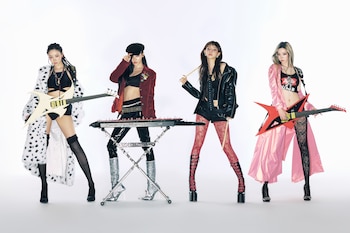 Cuatro mujeres jóvenes, las integrantes de Aespa, de pie sobre un fondo blanco, vestidas con atuendos rockeros y sosteniendo instrumentos musicales