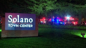 Letrero de Solano Town Center en un jardín durante la noche junto a patrullas de policía y camiones de bomberos con luces encendidas
