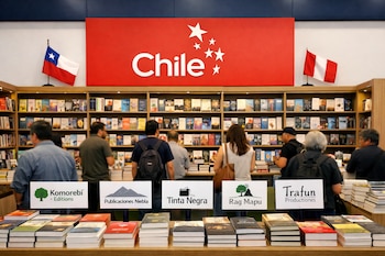 Stand con estanterías de libros, cartel "Chile" con estrellas, banderas de Chile y Perú, personas observando y mesas de exhibición con libros y carteles de editoriales.