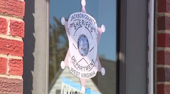 Insignia de la Oficina del Sheriff del condado de Jackson pegada en una puerta de vidrio entre paredes de ladrillo rojo