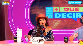 Mujer con sombrero, micrófono, teléfono móvil y vasos en un escritorio. Hombre con auriculares. Cartel con la palabra Catitejas. Pantalla trasera con texto SIN MAS QUE DECIR