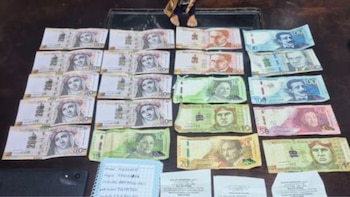 Billetes peruanos de diversas denominaciones extendidos sobre una mesa junto a una libreta de notas, recibos de papel y un teléfono móvil
