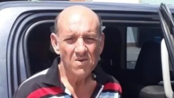 Primer plano de un hombre calvo de mediana edad, Hugo "Coco" Esteban, con polo a rayas negras, blancas y rojas, saliendo de un vehículo oscuro