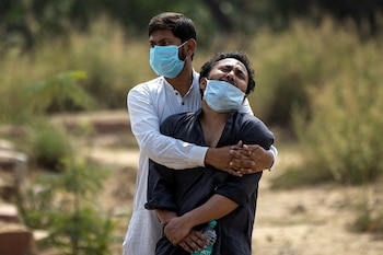 FILE PHOTO: A man is consoled by his relative as he sees the body of his father, who died from the coronavirus disease (COVID-19), before his burial at a graveyard in New Delhi, India, April 16, 2021. REUTERS/Danish Siddiqui/File Photo